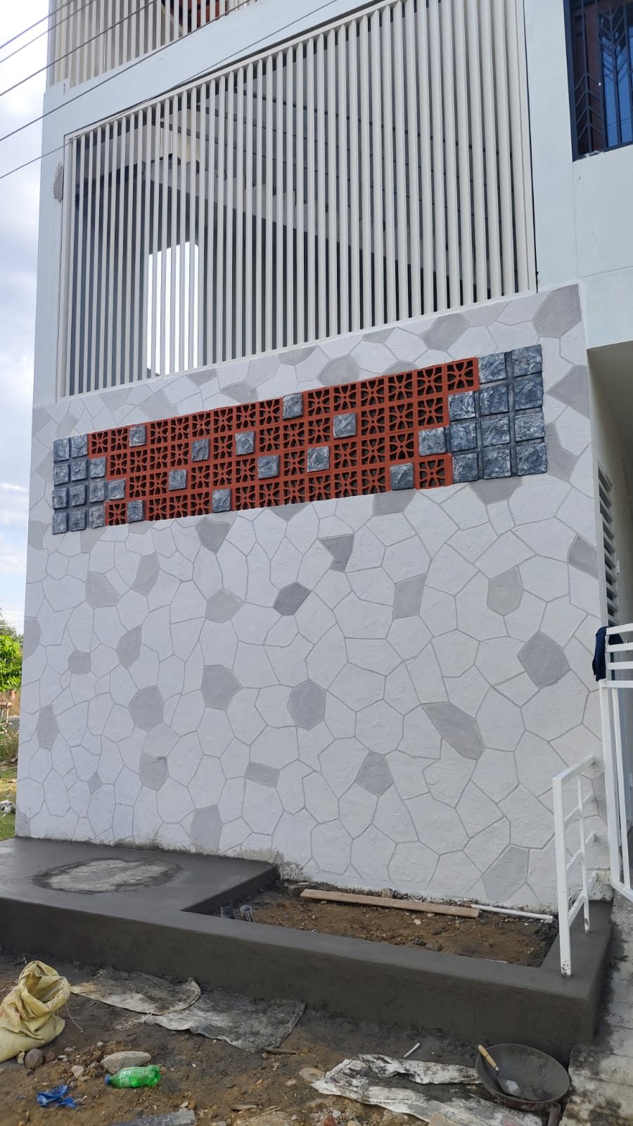 Exterior building facade finished with a grey stone pattern and terracotta inlay