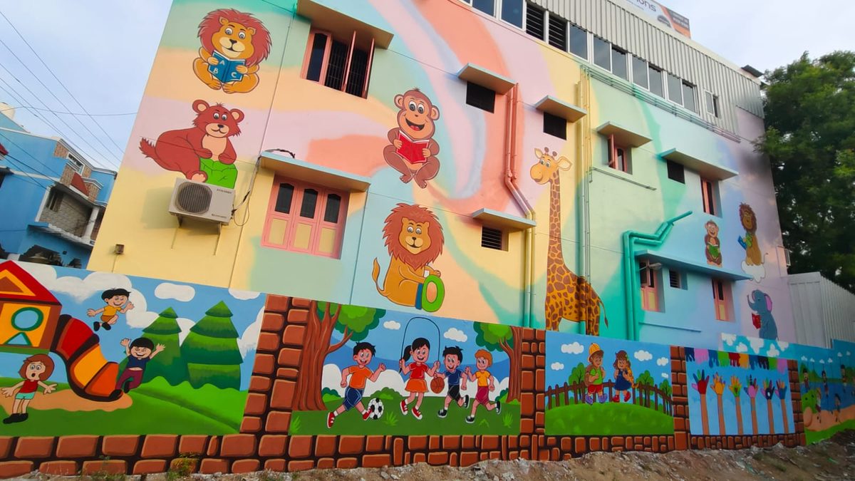 School building exterior mural with lions, monkeys and a giraffe