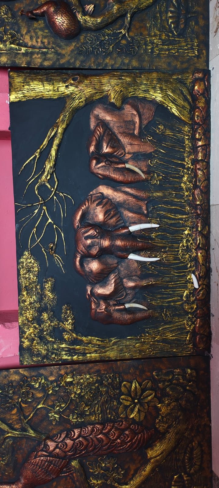Copper-finish relief panel of an elephant family among trees