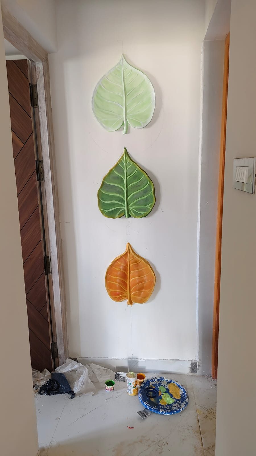 Three large painted leaf-shaped relief sculptures in green and orange