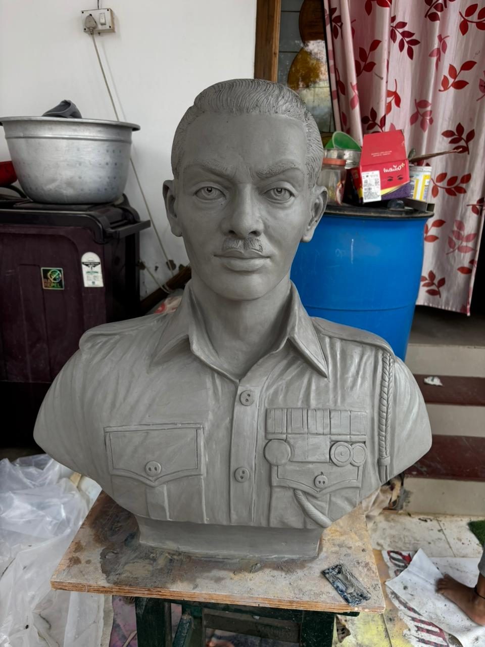 Cement-finish portrait bust sculpture of a young man wearing a uniform shirt