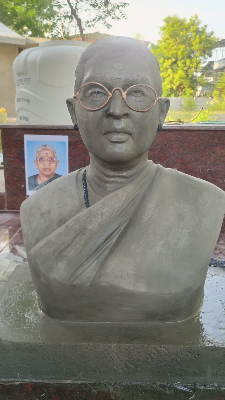 Cement-finish memorial bust sculpture of a woman wearing glasses