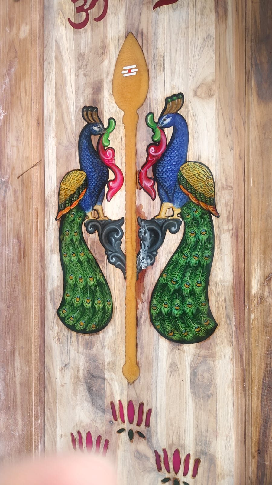 Carved wood panel of mirrored peacocks around a vel, with Om above